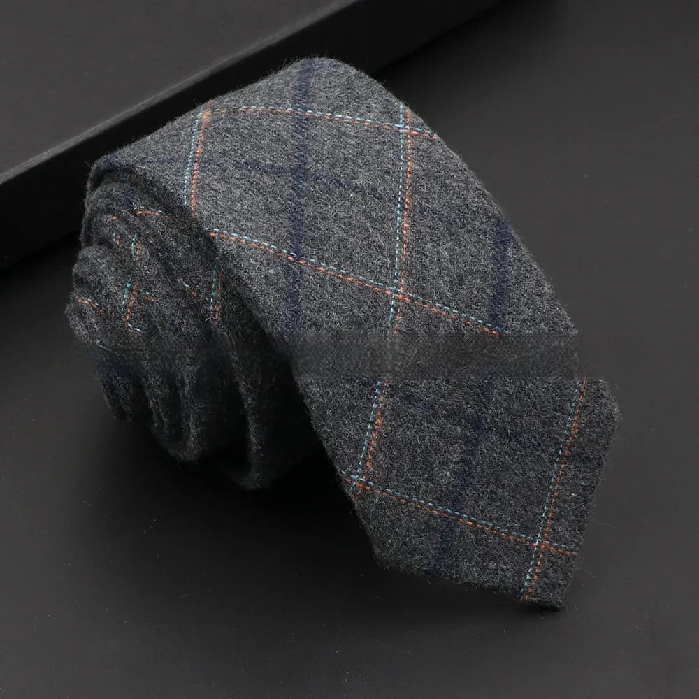 Rolled gray wool tie with blue and orange plaid pattern on black surface