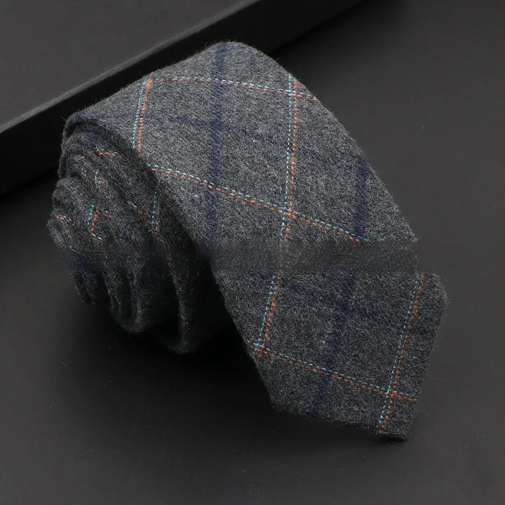 Rolled gray wool tie with blue and orange plaid pattern on black surface