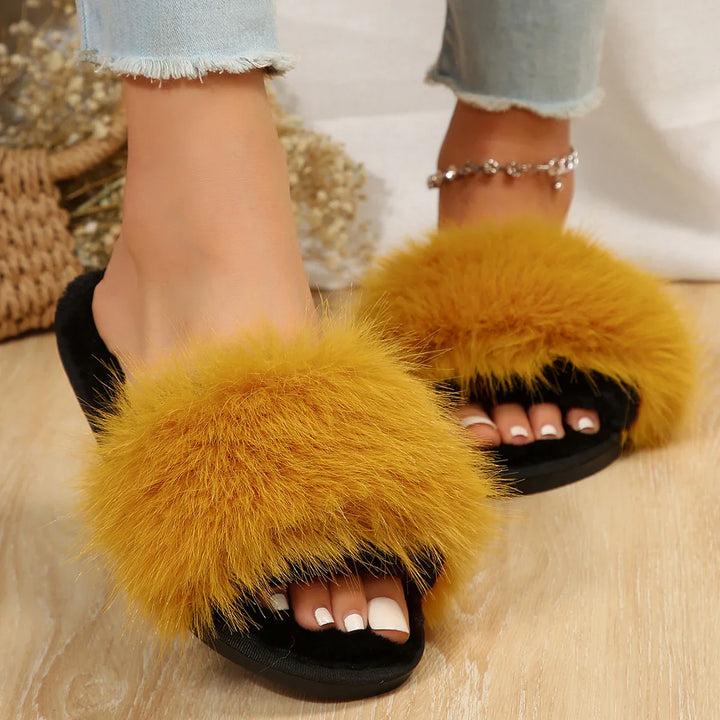 woman wearing yellow furry slippers with black sole on wooden floor and light blue jeans