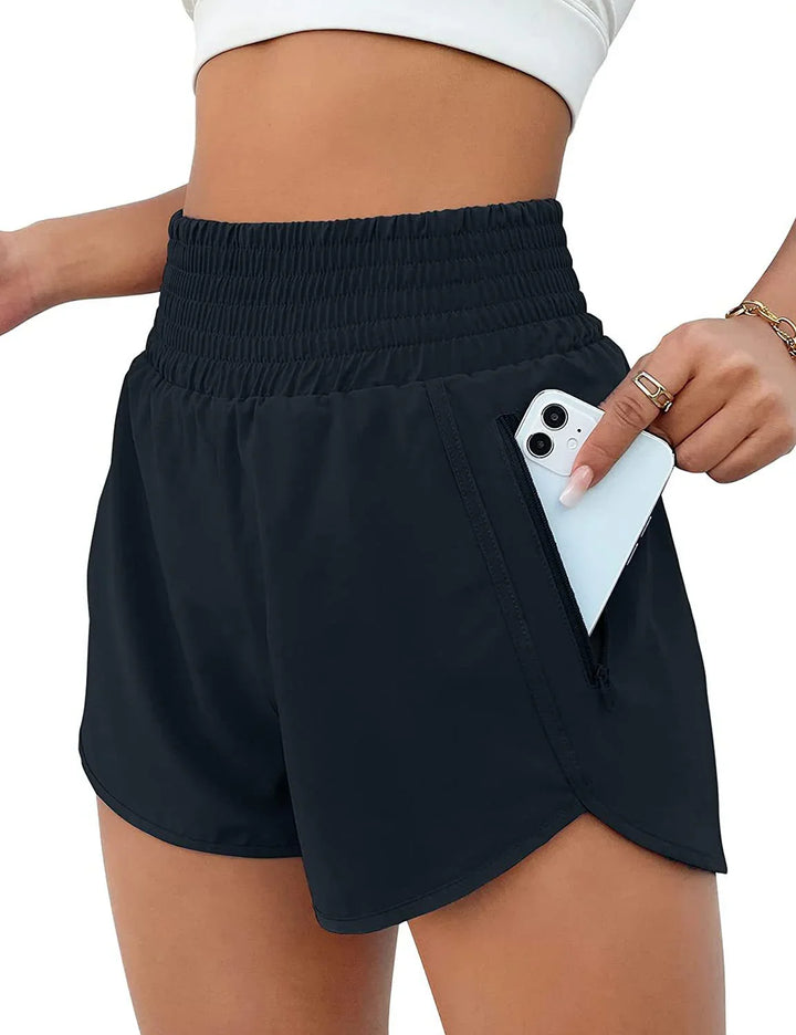 Close-up of woman wearing black high-waisted athletic shorts with zippered pocket holding smartphone