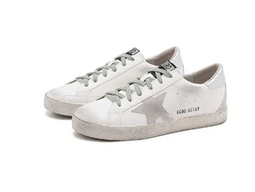White low-top Golden Goose sneakers with gray star accents and gray laces on white background