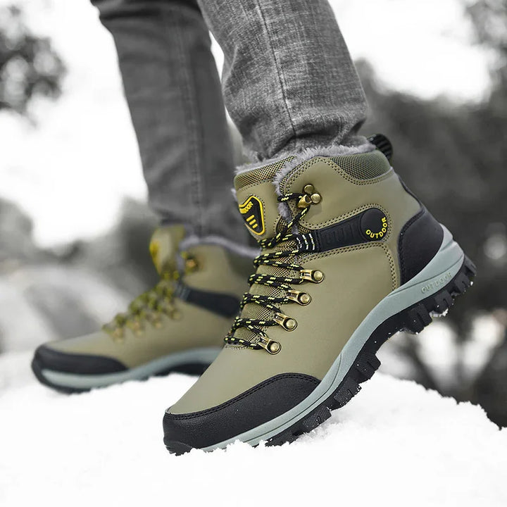Close-up of olive green outdoor hiking boots with black soles and yellow laces on snowy ground
