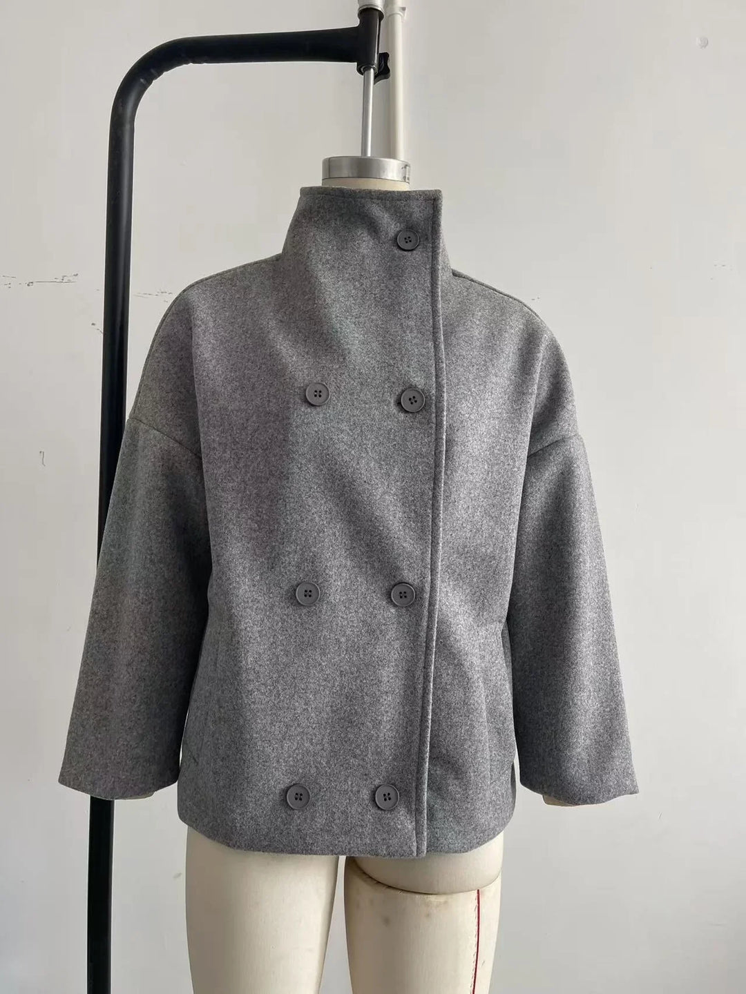 Gray double-breasted wool coat with high collar on mannequin against white background