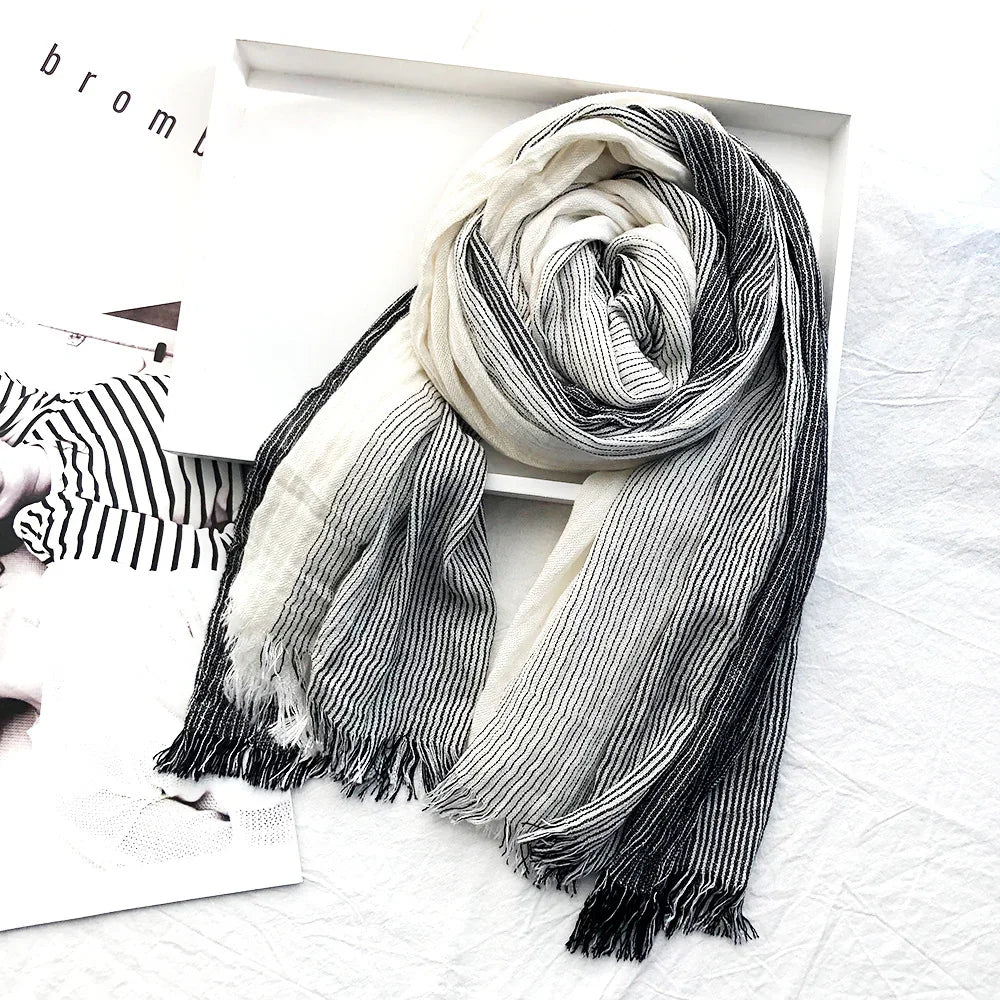 Black and white striped soft scarf with fringes displayed on white surface and box