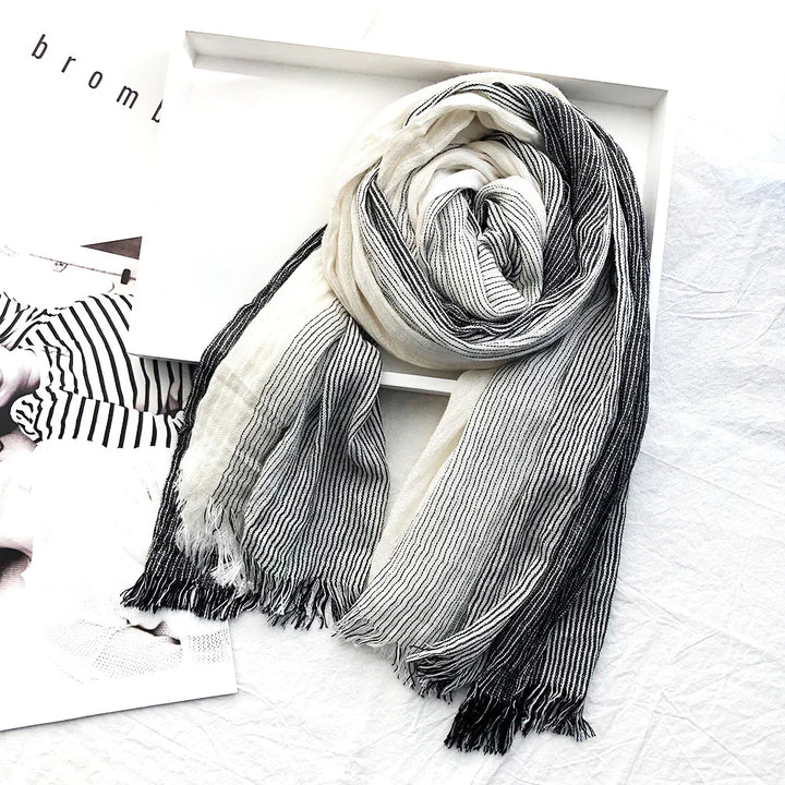 Black and white striped soft scarf with fringes displayed on white surface and box
