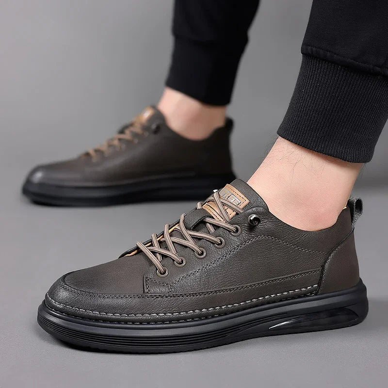 men's casual dark brown leather sneakers with black soles and beige laces on gray background