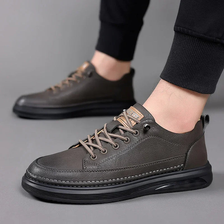 men's casual dark brown leather sneakers with black soles and beige laces on gray background