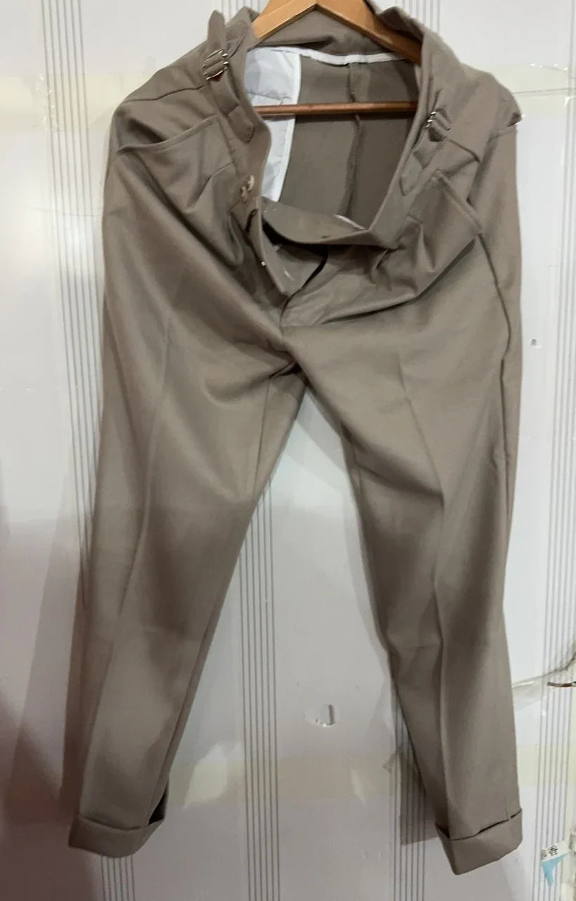 Beige formal trousers hanging on wooden hanger against white paneled wall