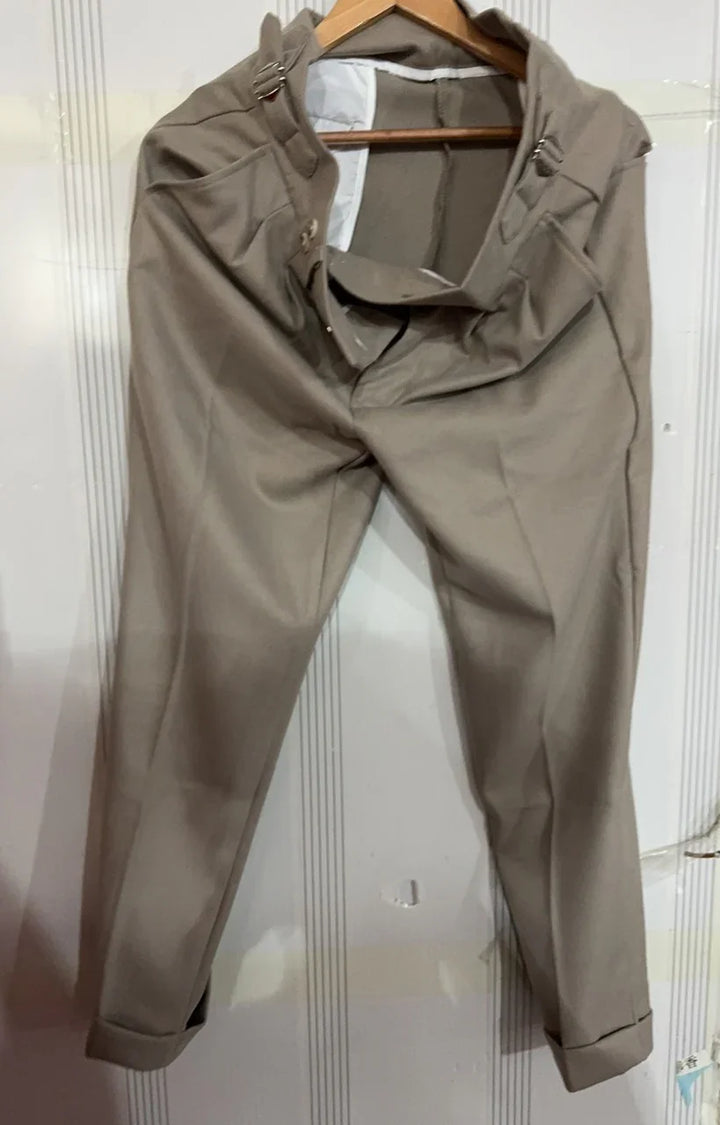 Beige formal trousers hanging on wooden hanger against white paneled wall