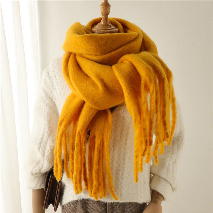Cozy mustard yellow wool scarf with fringes on mannequin wearing white knit sweater and brown pants