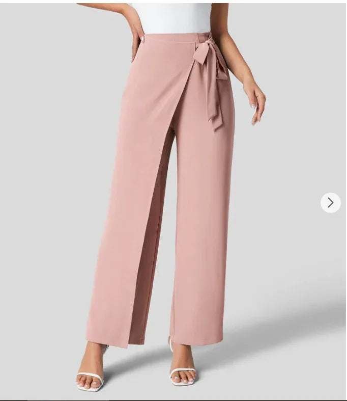 Women’s blush pink high-waist wide-leg pants with front wrap detail and side bow, paired with white heeled sandals