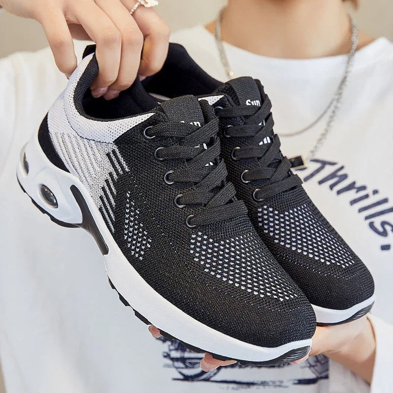 Black and white breathable mesh running shoes with thick white soles and air cushion soles held by a person