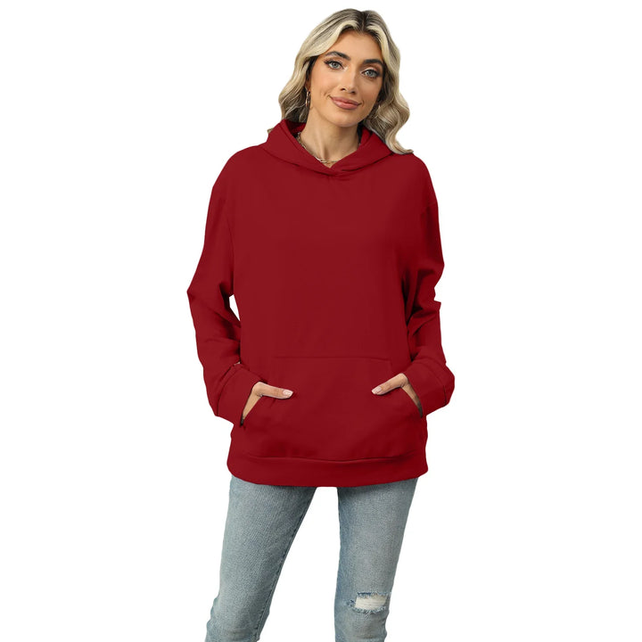 Woman wearing a red hoodie with front pocket and light blue ripped jeans