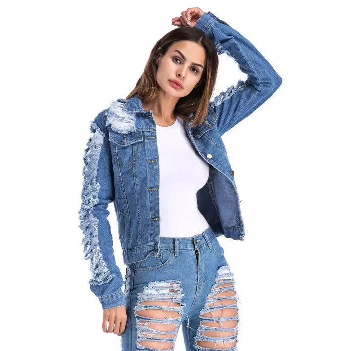 Woman wearing distressed denim jacket and ripped jeans over white top on white background