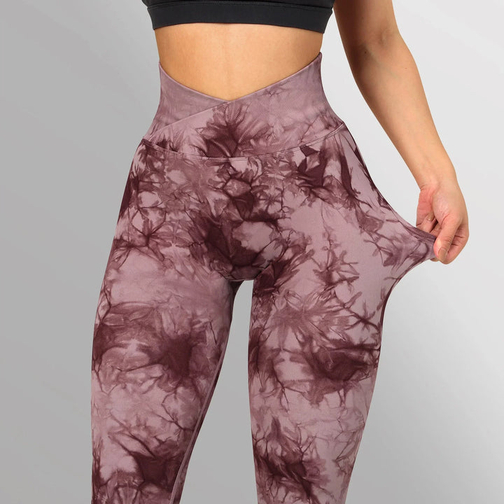 High-waisted purple tie-dye leggings with stretchy fabric and a black sports bra