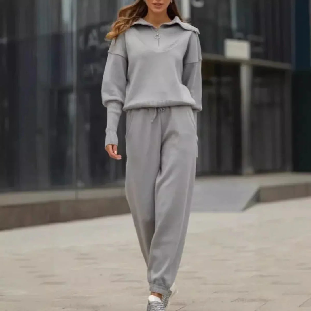 Woman walking outdoors wearing a light gray sweatshirt and matching jogger pants with sneakers