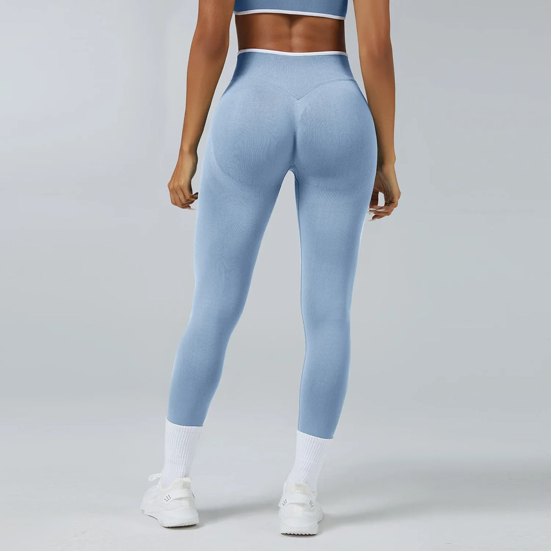 Woman wearing light blue seamless high-waisted leggings and white sneakers, back view on gray background