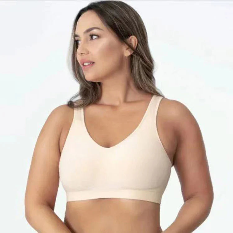 Woman wearing a beige seamless wireless bra with wide straps against white background
