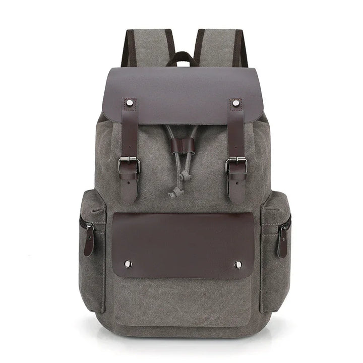 Gray canvas backpack with brown leather straps, front flap pocket, and side zippered compartments