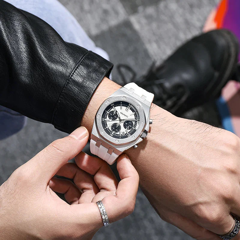 Person adjusting silver chronograph watch with white band, wearing black leather jacket and silver rings