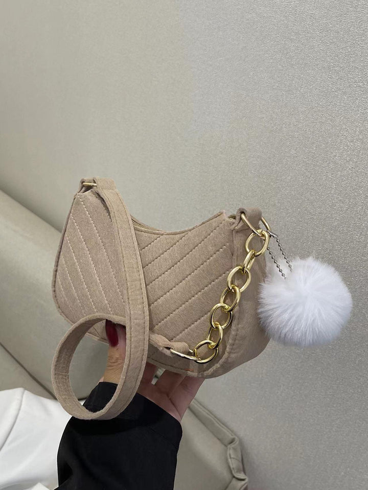Beige quilted shoulder bag with gold chain and white fluffy pom-pom accessory