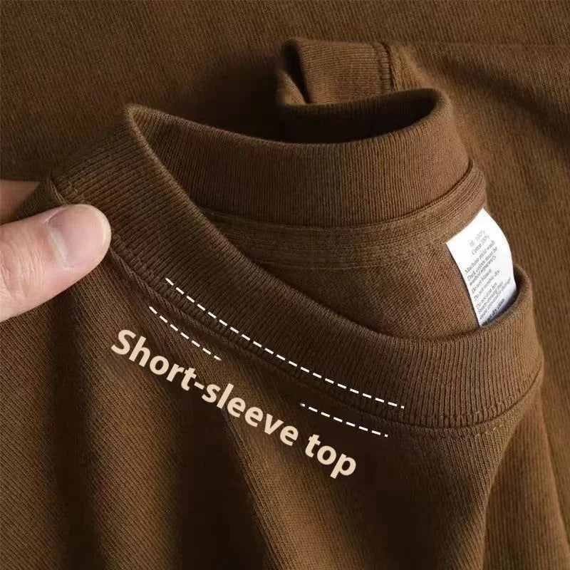 Brown short-sleeve top fabric close-up with hand holding neckline and clothing label visible