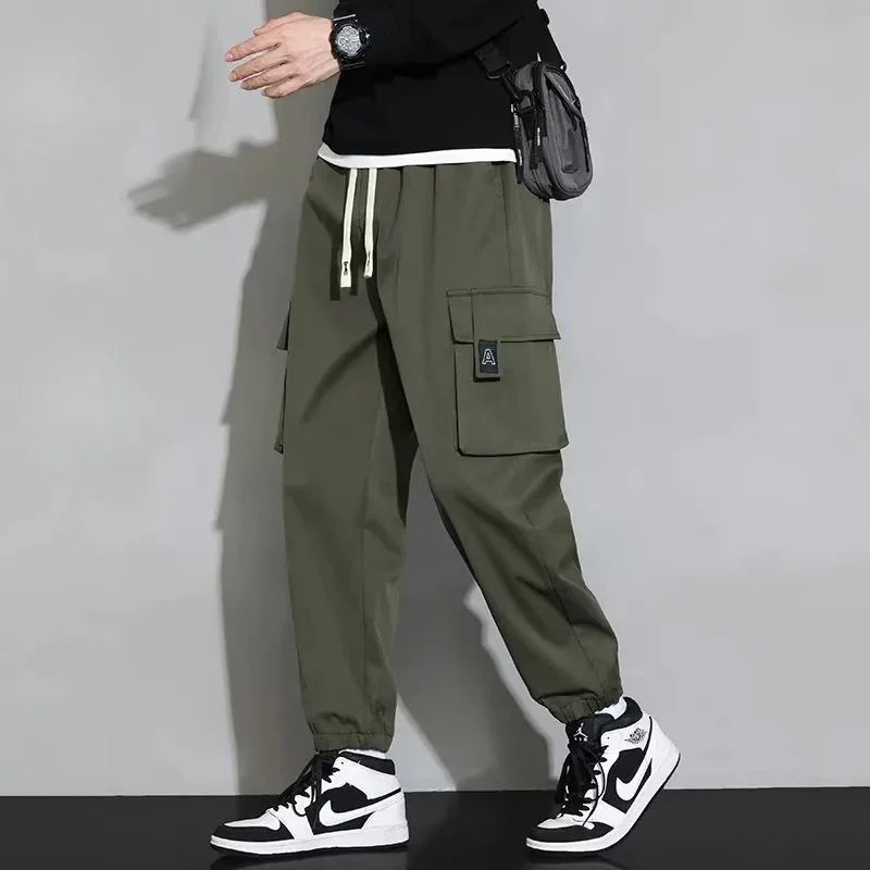 Person wearing olive green cargo jogger pants with white drawstrings and black-and-white Nike sneakers