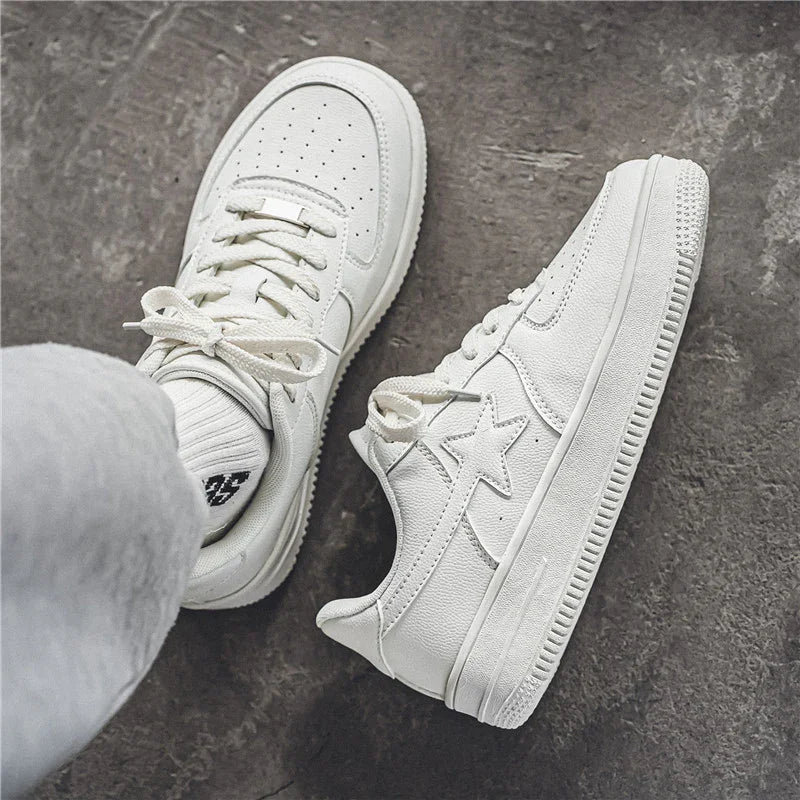 Pair of white leather sneakers with star design on concrete floor, casual streetwear shoes