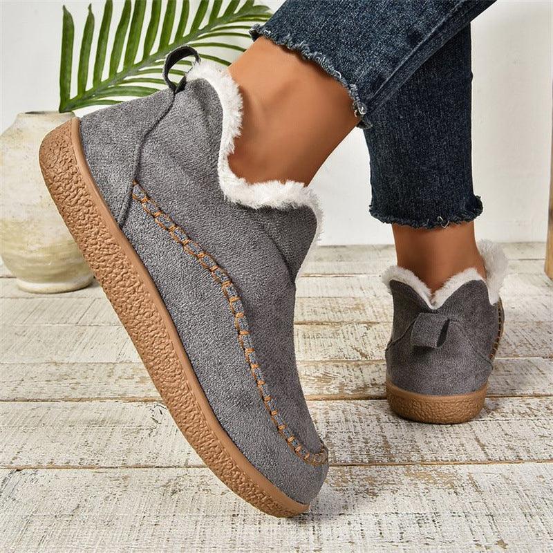 Cozy gray slip-on shoes with white fur lining and textured brown sole worn with frayed hem jeans indoors