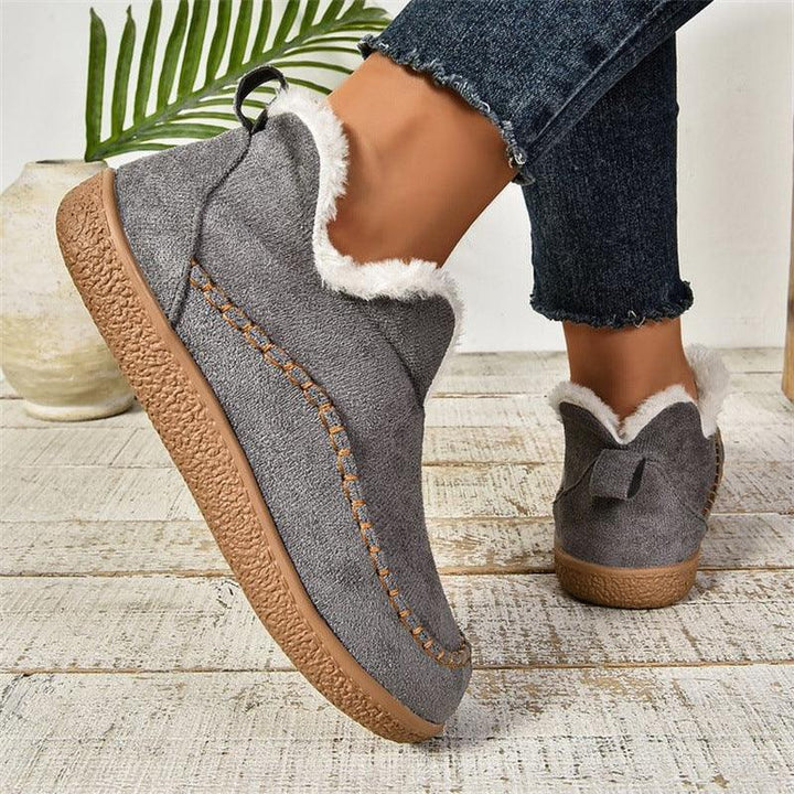 Cozy gray slip-on shoes with white fur lining and textured brown sole worn with frayed hem jeans indoors