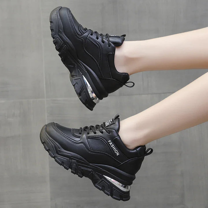 Black chunky platform sneakers with thick soles and the word 'FASHION' on the side, worn on feet