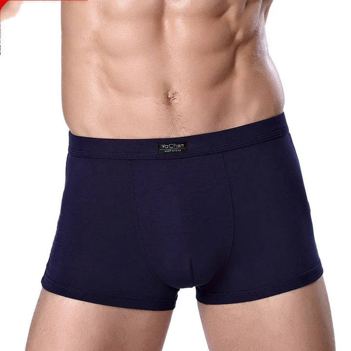 Close-up of a fit male torso wearing dark navy blue boxer briefs with YaChen label