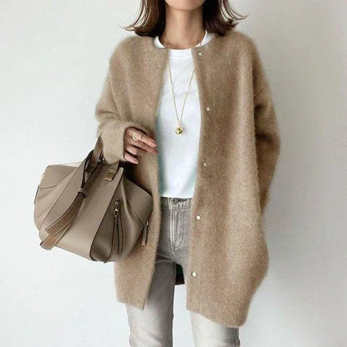 Woman wearing beige fuzzy cardigan, white t-shirt, gray jeans, and carrying taupe leather handbag