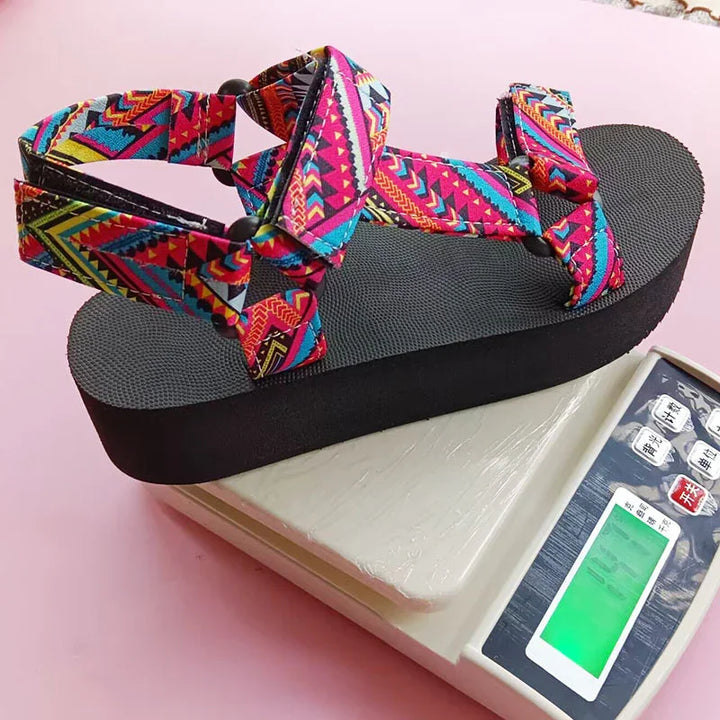Colorful patterned platform sandal with black sole on digital weighing scale against pink background