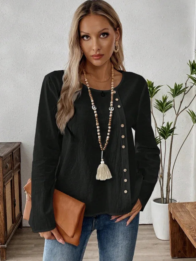 Woman in black buttoned long-sleeve top with wooden bead tassel necklace and brown clutch purse