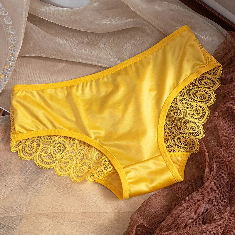 Yellow satin women's underwear with intricate lace trim on soft beige and brown fabric background