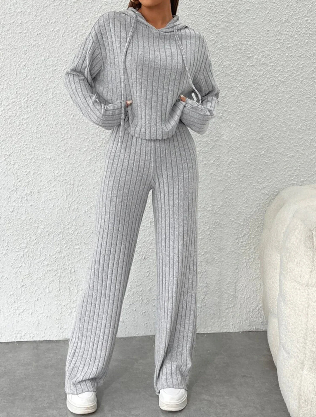 Woman wearing cozy grey ribbed knit hoodie and matching pants loungewear with white sneakers