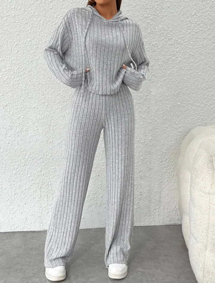 Woman wearing cozy grey ribbed knit hoodie and matching pants loungewear with white sneakers
