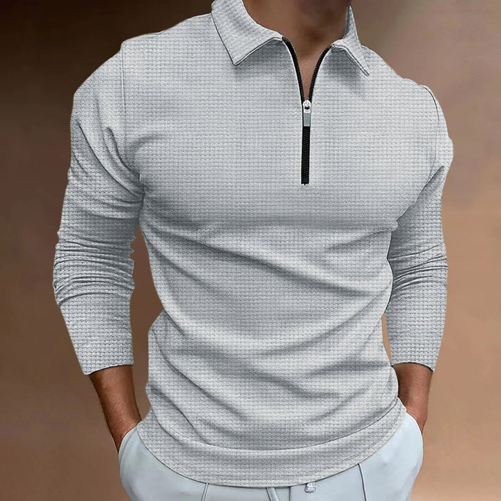 Man wearing light grey textured long-sleeve zip-up shirt with collar and hands in pockets