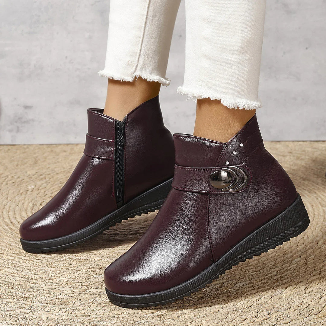 Women's maroon ankle boots with side zipper, decorative buckle, and black wedge sole