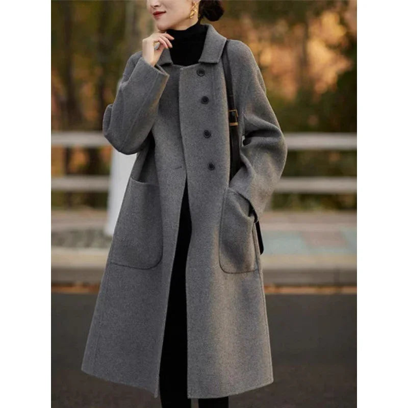 Woman wearing a long grey wool coat with large pockets and black buttons outdoors