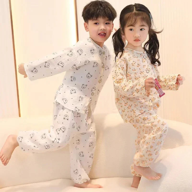 Two young children in cute patterned pajamas, boy with bear print and girl with floral print, playing indoors