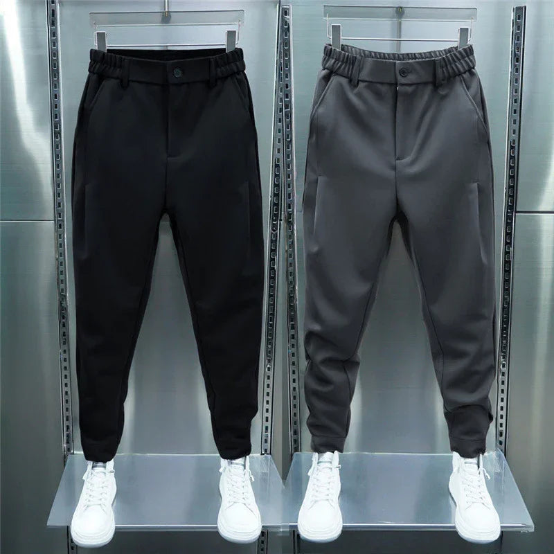 Black and gray men's casual jogger pants with elastic waist and white sneakers on industrial metal display