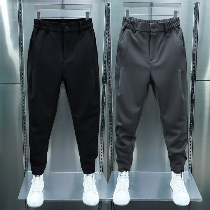 Black and gray men's casual jogger pants with elastic waist and white sneakers on industrial metal display