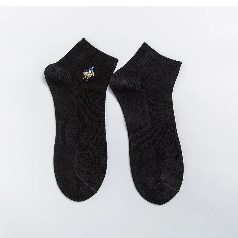 Pair of black ankle socks with embroidered blue and beige horse rider detail on plain background