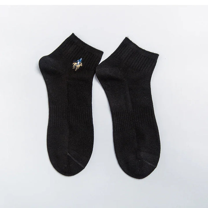 Pair of black ankle socks with embroidered blue and beige horse rider detail on plain background