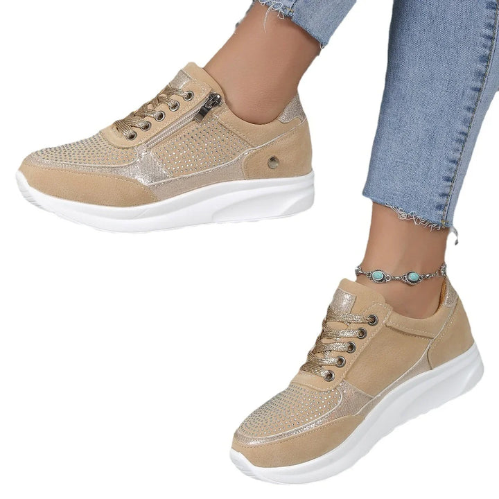 Women's beige casual sneakers with rhinestone accents, white soles, zipper detail, worn with blue jeans and turquoise anklet