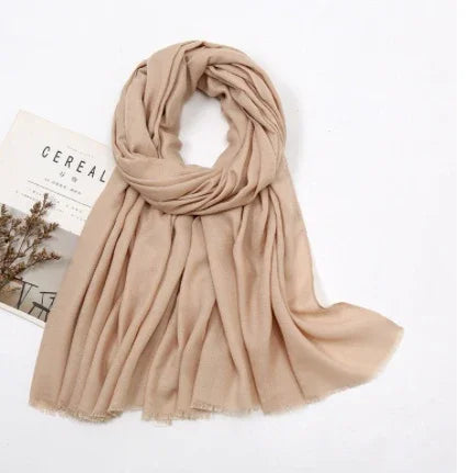 Soft beige scarf neatly arranged on white surface with minimalistic magazine and dried flowers