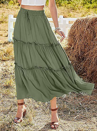 Woman wearing an olive green tiered maxi skirt and white crop top outdoors near hay bale