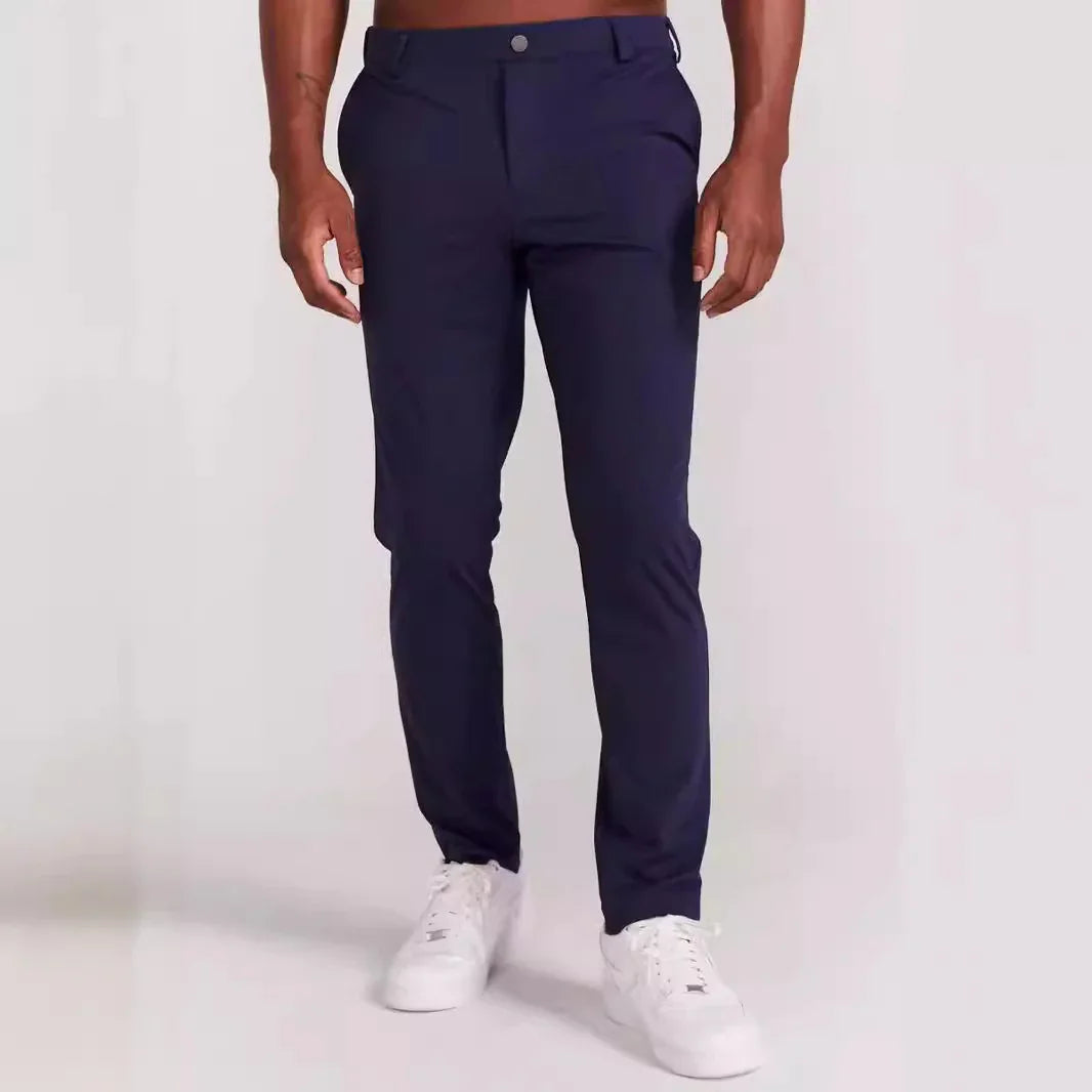 Men's slim fit navy blue trousers with side pockets and white sneakers on plain background